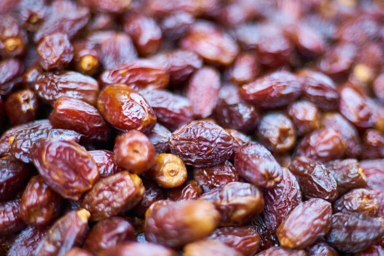 Dried dates piled together, showing their wrinkled reddish-brown skins and varied sizes.